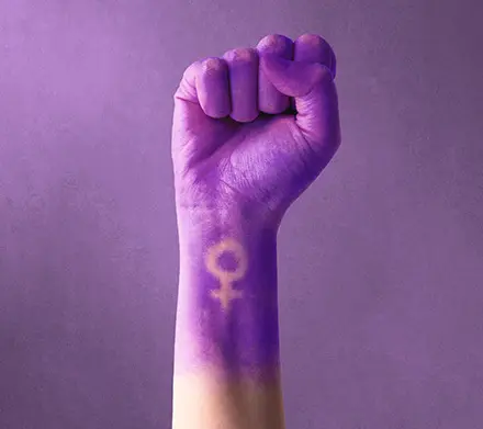 Pu&ntilde;o cerrado pintado de morado con el s&iacute;mbolo de la mujer por el 8M.