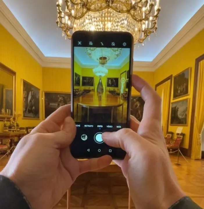 Persona haciendo una fotograf&iacute;a con su m&oacute;vil a una sala de un museo