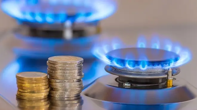 Bollete de gas junto a monedas apiladas