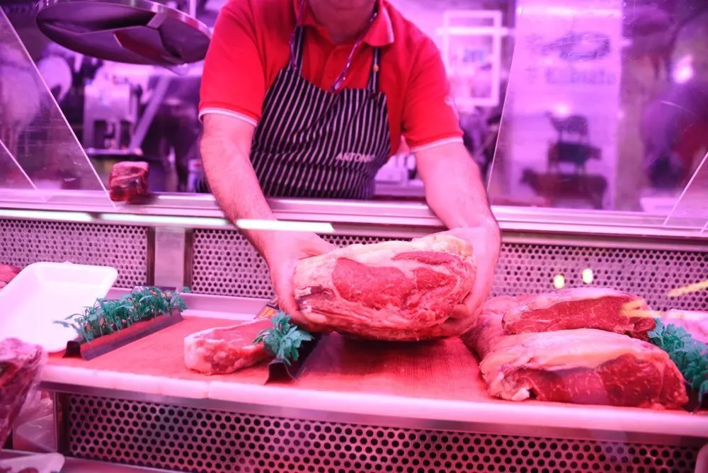 Carnicero cogiendo con sus manos un producto en su carnicer&iacute;a