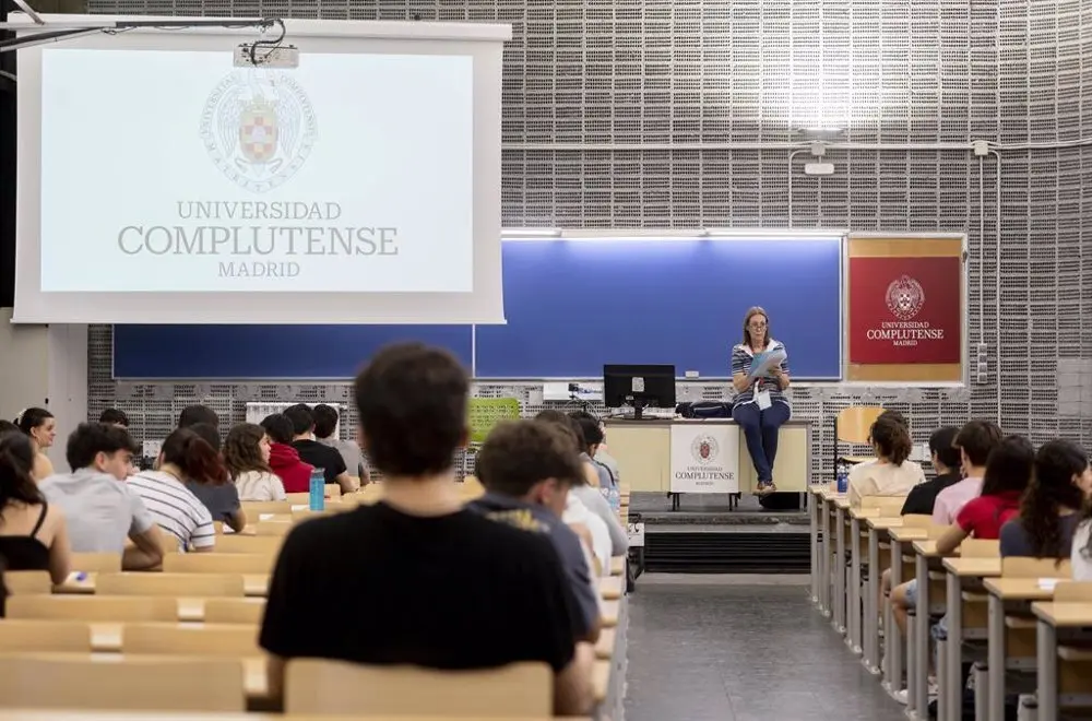 Varios estudiantes de la universidad complutense sentados atendiendo a la profesora