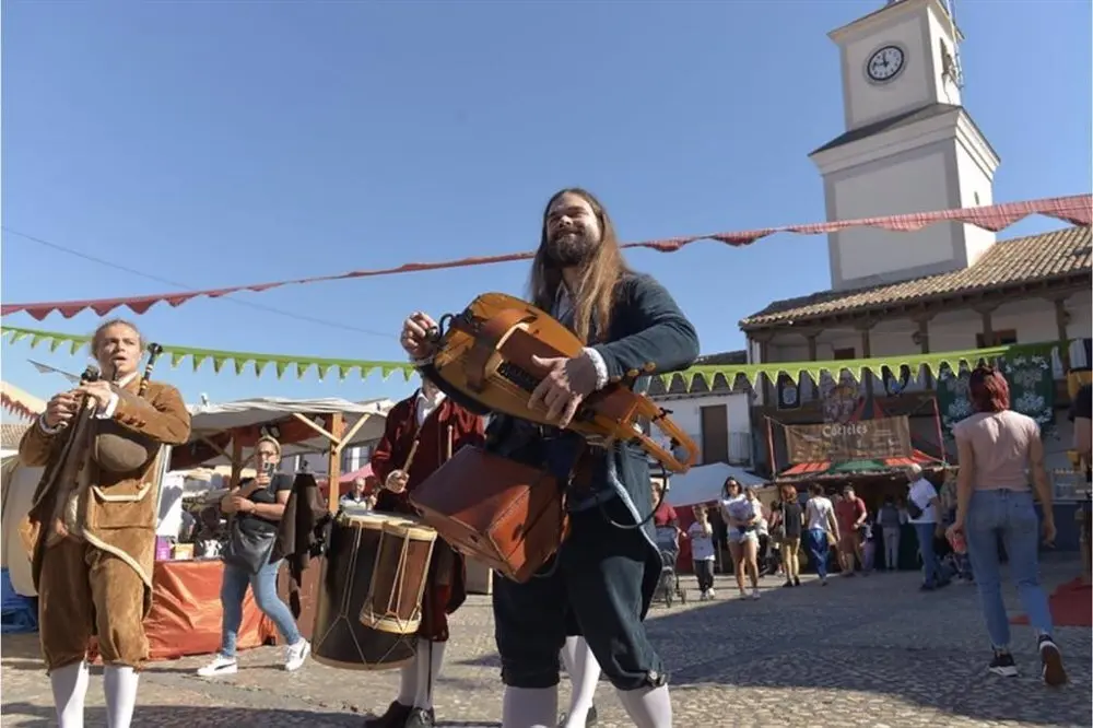 M&uacute;sicos con trajes medievales tocando diferentes instrumentos de la &eacute;poca en una plaza de pueblo 
