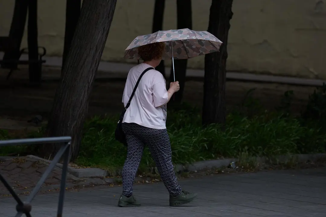 Una mujer se protege de la lluvia con un paraguas.