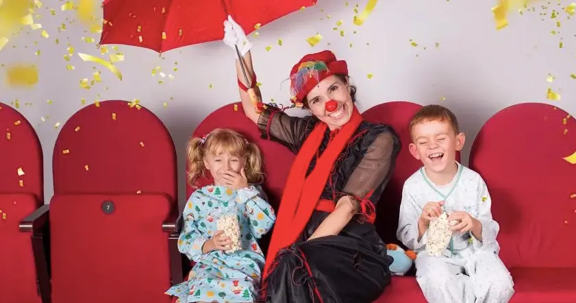 Una mujer vestida de payaso alegra junto a dos ni&ntilde;os en pijama