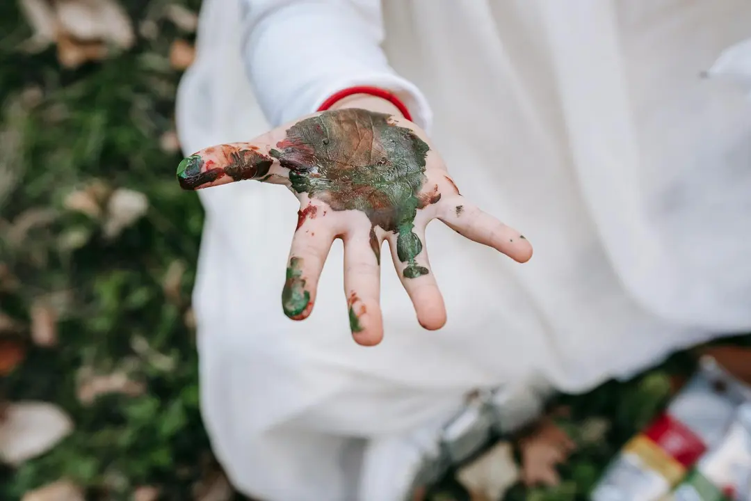 Imagen de archivo de la mano de un menor pintada de verde y marr&oacute;n.