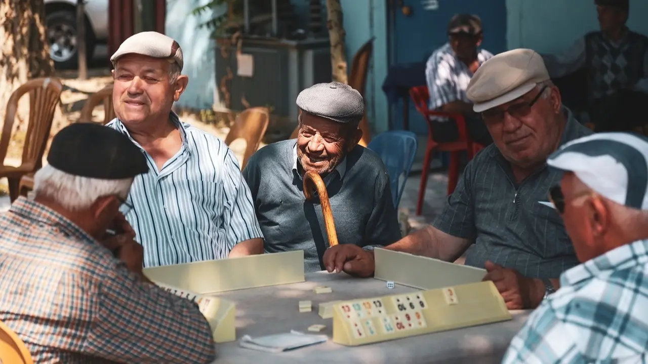 Un grupo de cinco se&ntilde;ores mayores jugando al Rummy.