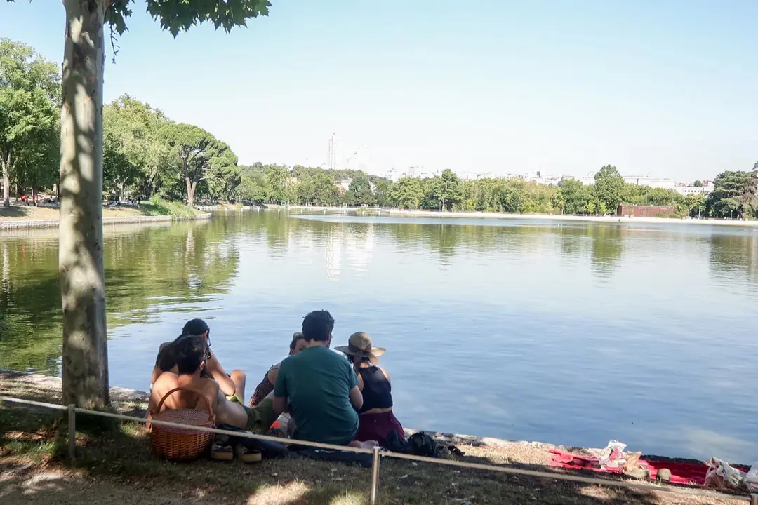 Personas sentadas en la orilla del lago de la casa de campo. Imagen de archivo.