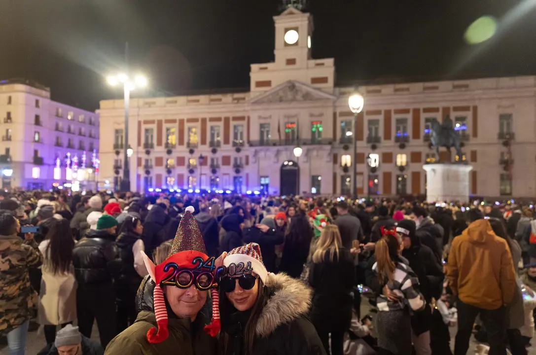 Imagen de archivo. Dos personas disfrazadas se hacen una foto con el reloj de fondo, antes de las campanadas de Nochevieja 2023, en la Puerta del Sol.