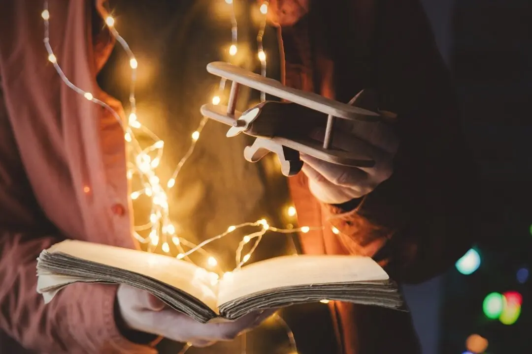 Persona con un libro, luces y un juguete. Imagen de archivo.