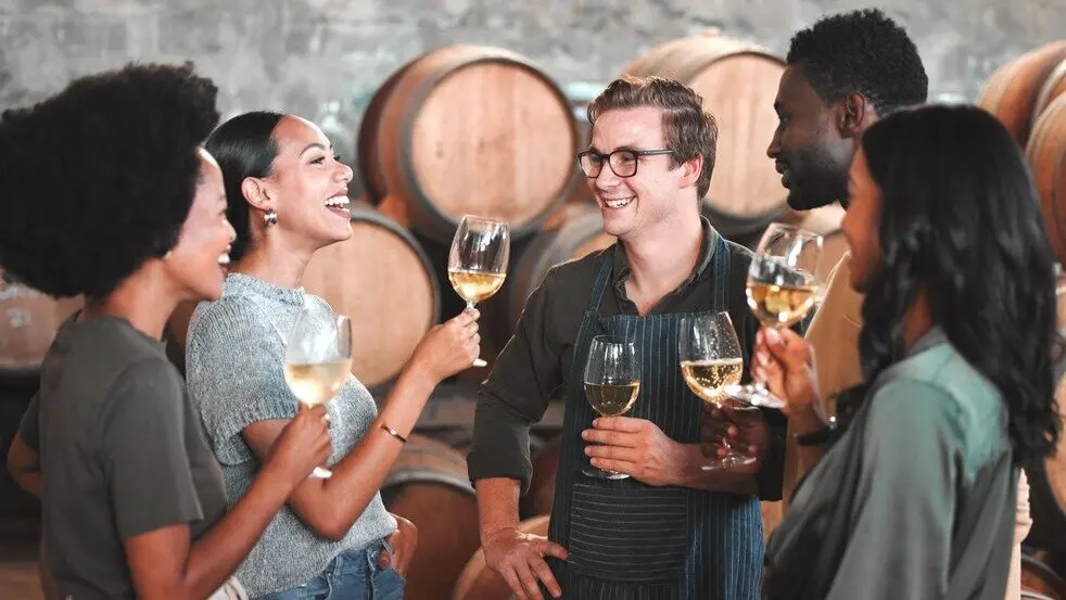 Grupo de amigos degustando vino en una bodega. Imagen de archivo.