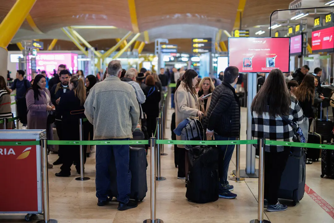 Varias personas con maletas hacen cola en la terminal T4 del aeropuerto de Adolfo Su&aacute;rez-Madrid Barajas.