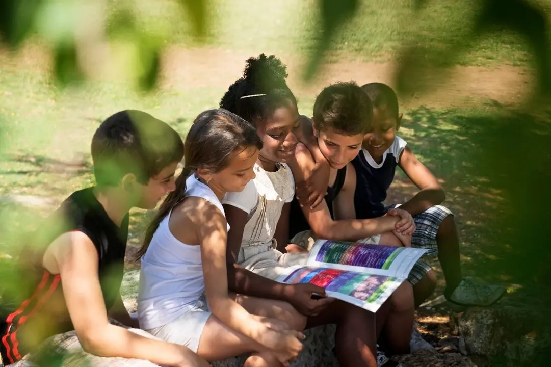 Ni&ntilde;os leyendo al aire libre. Imagen de archivo.