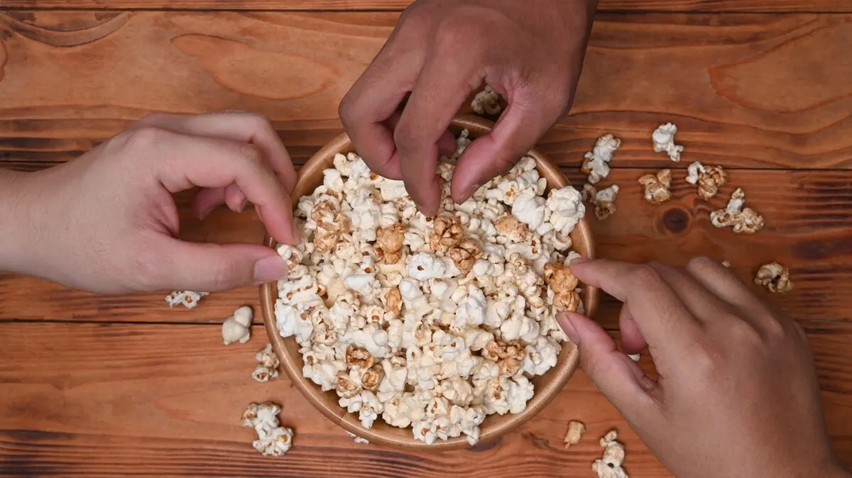 Personas agarrando palomitas. Imagen de archivo.
