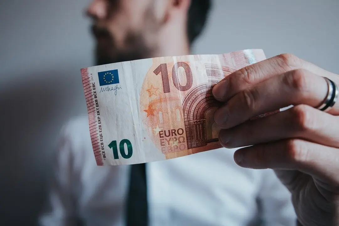 Hombre sosteniendo un billete de diez euros. Imagen de archivo.