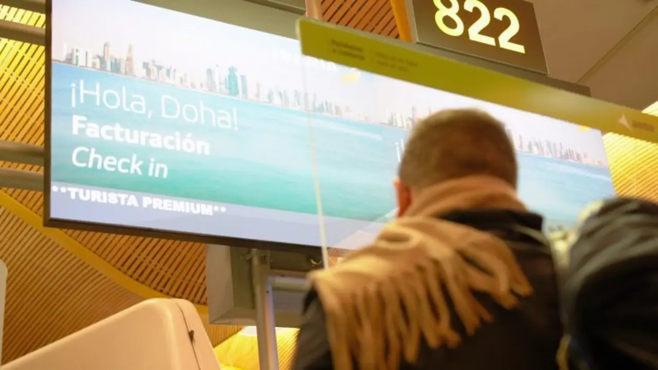 Un hombre viendo un cartel del vuelo Madrid Doha que une con Oriente Medio. 