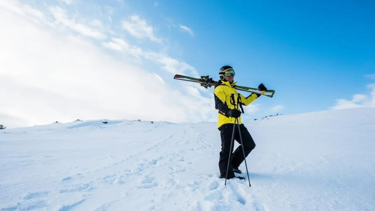 sportsman in helmet standing with ski sticks on snow in mountains