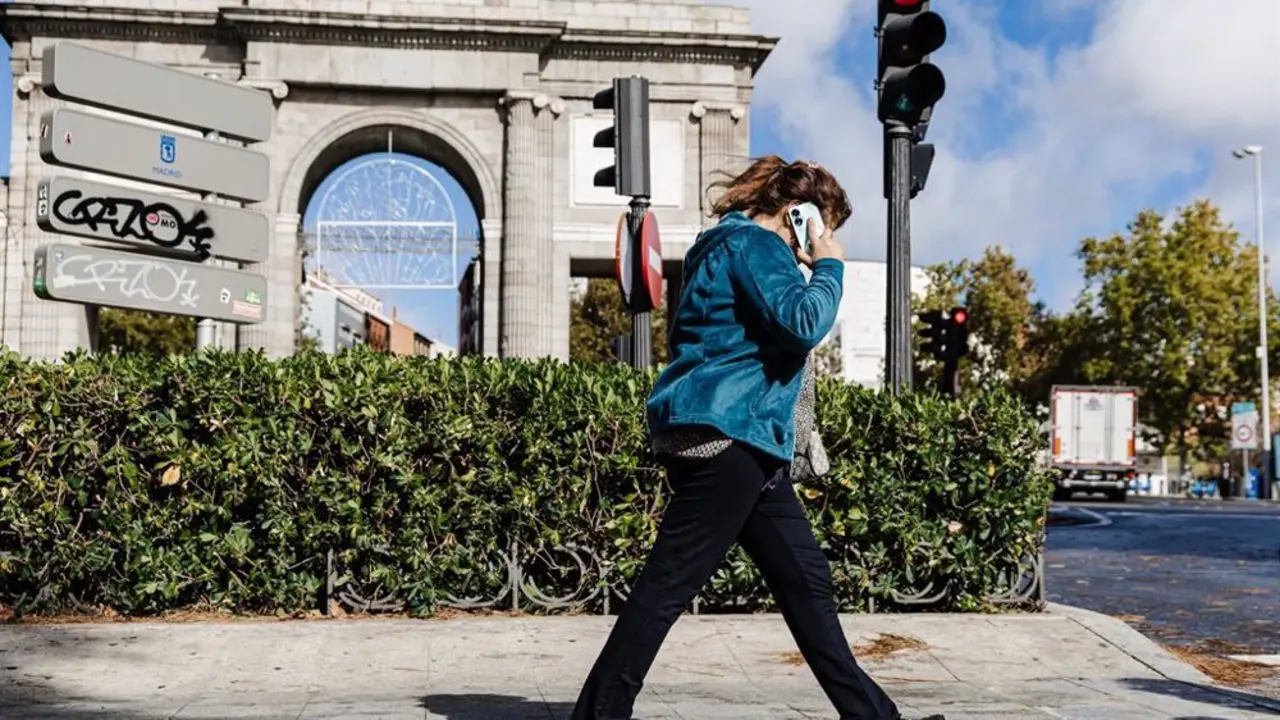Se&ntilde;ora hablando por tel&eacute;fono mientras pasea frente a la Puerta de Alcal&aacute;