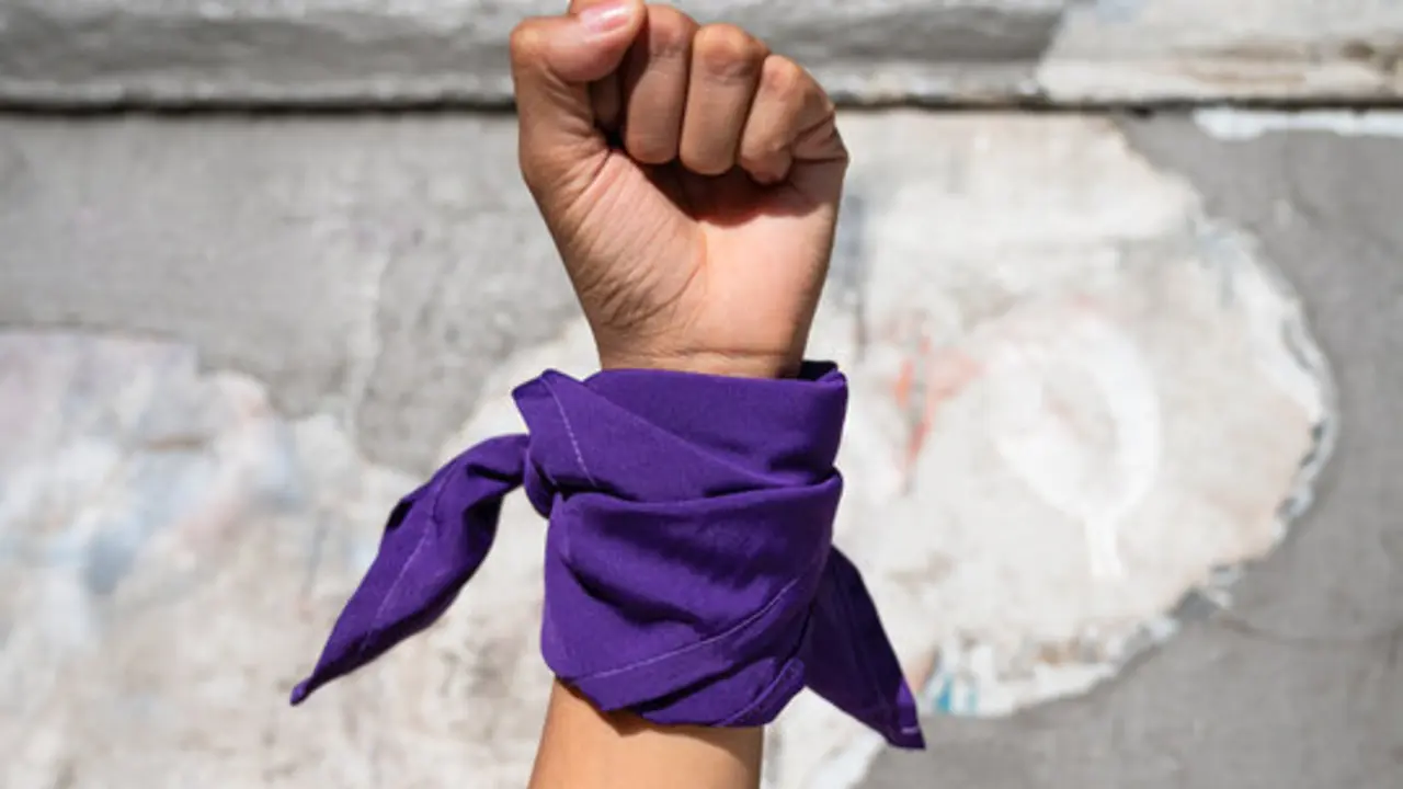 Pu&ntilde;o cerrado con pa&ntilde;uelo morado atado a la mu&ntilde;eca