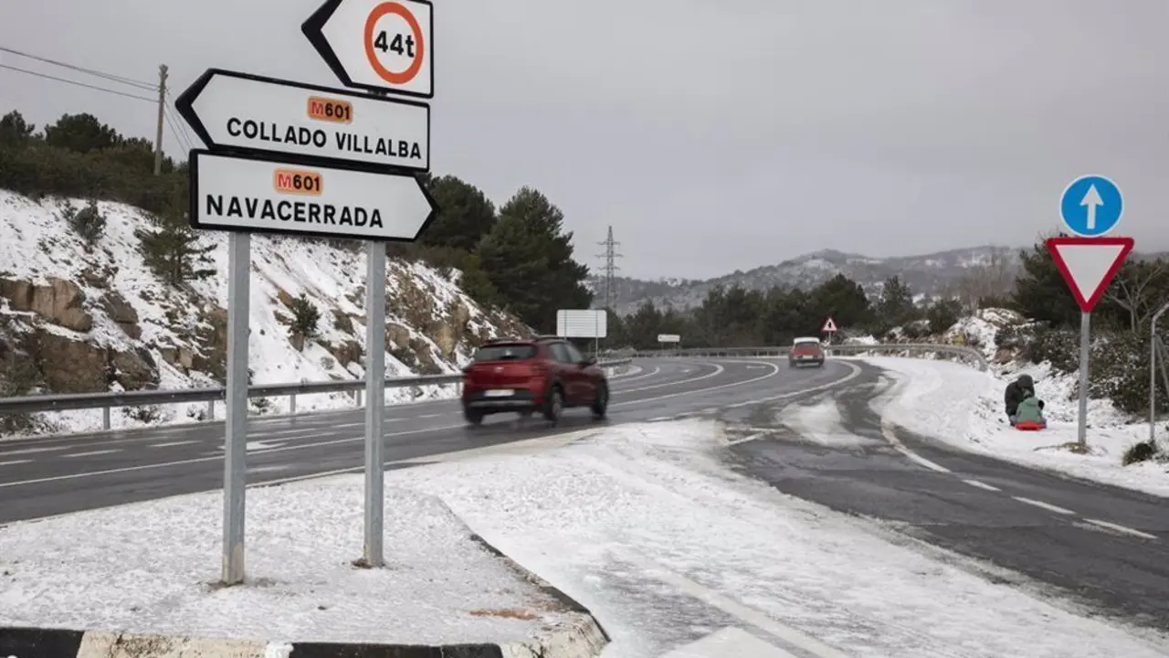 Carretera nevada junto a una se&ntilde;al de tr&aacute;fico que indica dos direcciones: hacia Collado Villalba y hacia Navacerrada