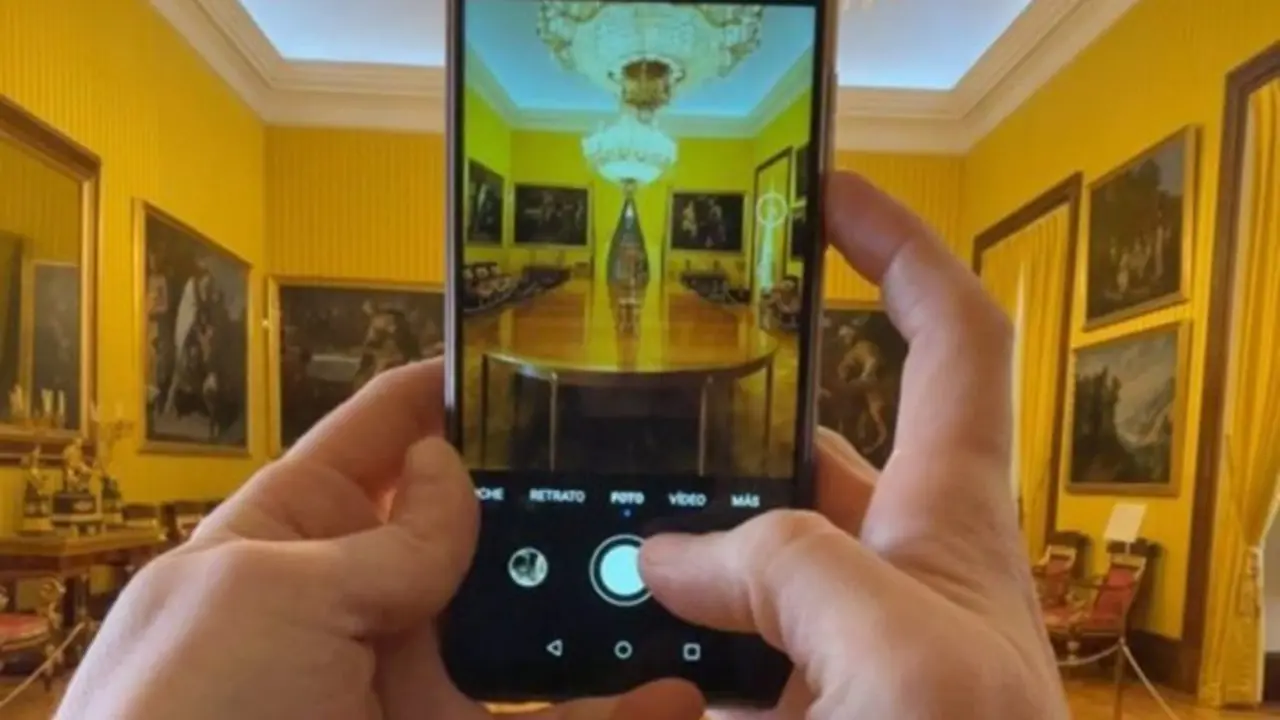 Persona haciendo una fotograf&iacute;a con su m&oacute;vil a una sala de un museo