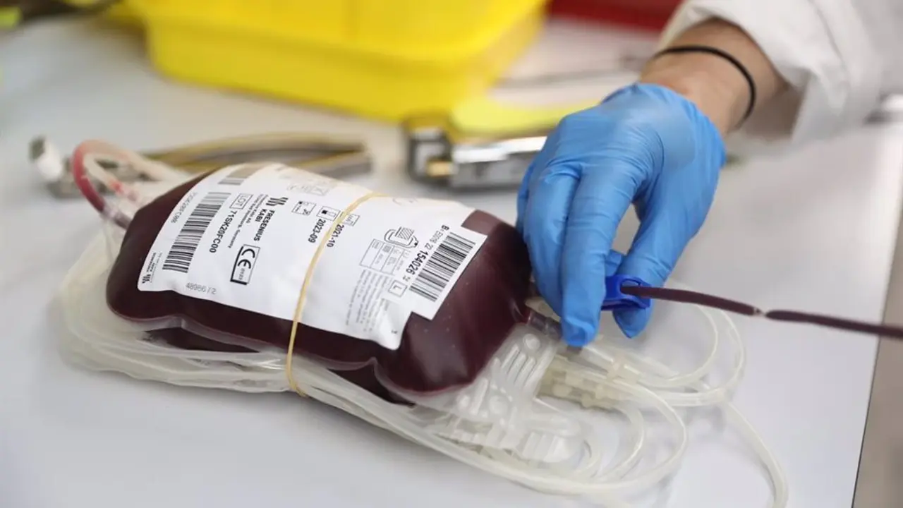 Enfermero con un guante azul sosteniendo una bolsa de sangre donada