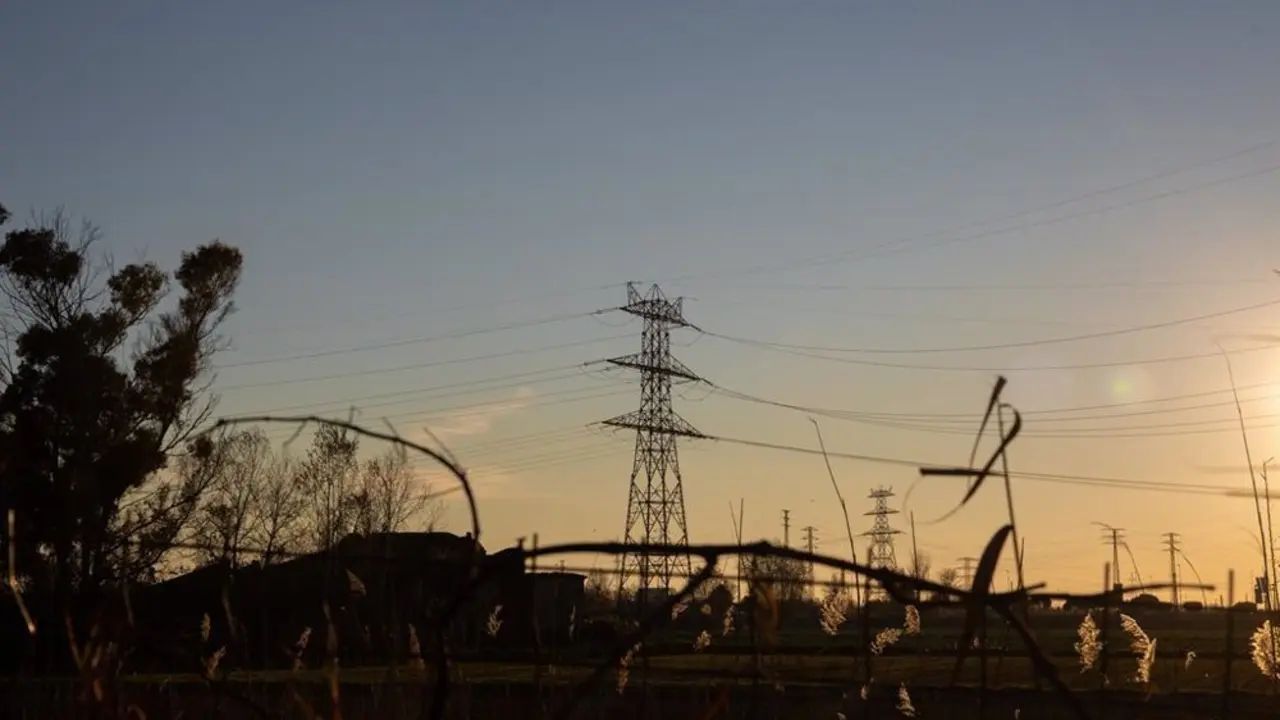 Torre de transmisi&oacute;n de electricidad con un atardecer de fondo
