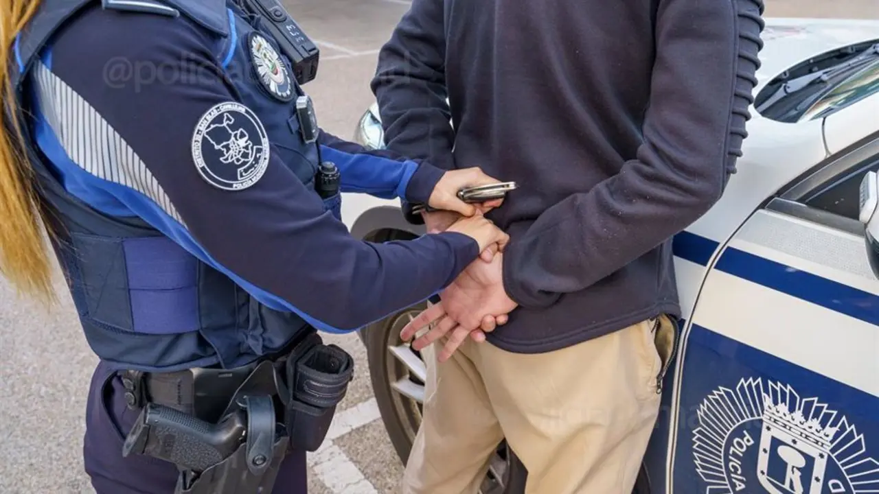 Polic&iacute;a esposando a un hombre frente a un veh&iacute;culo policial de la Polic&iacute;a Municipal de Madrid