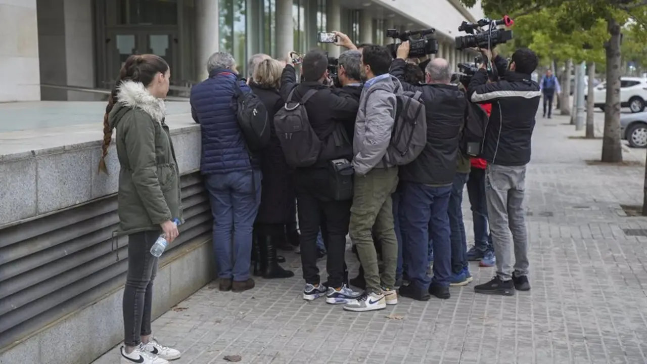 Personas y prensa aglomerada frente a una puerta de un edificio en Madrid