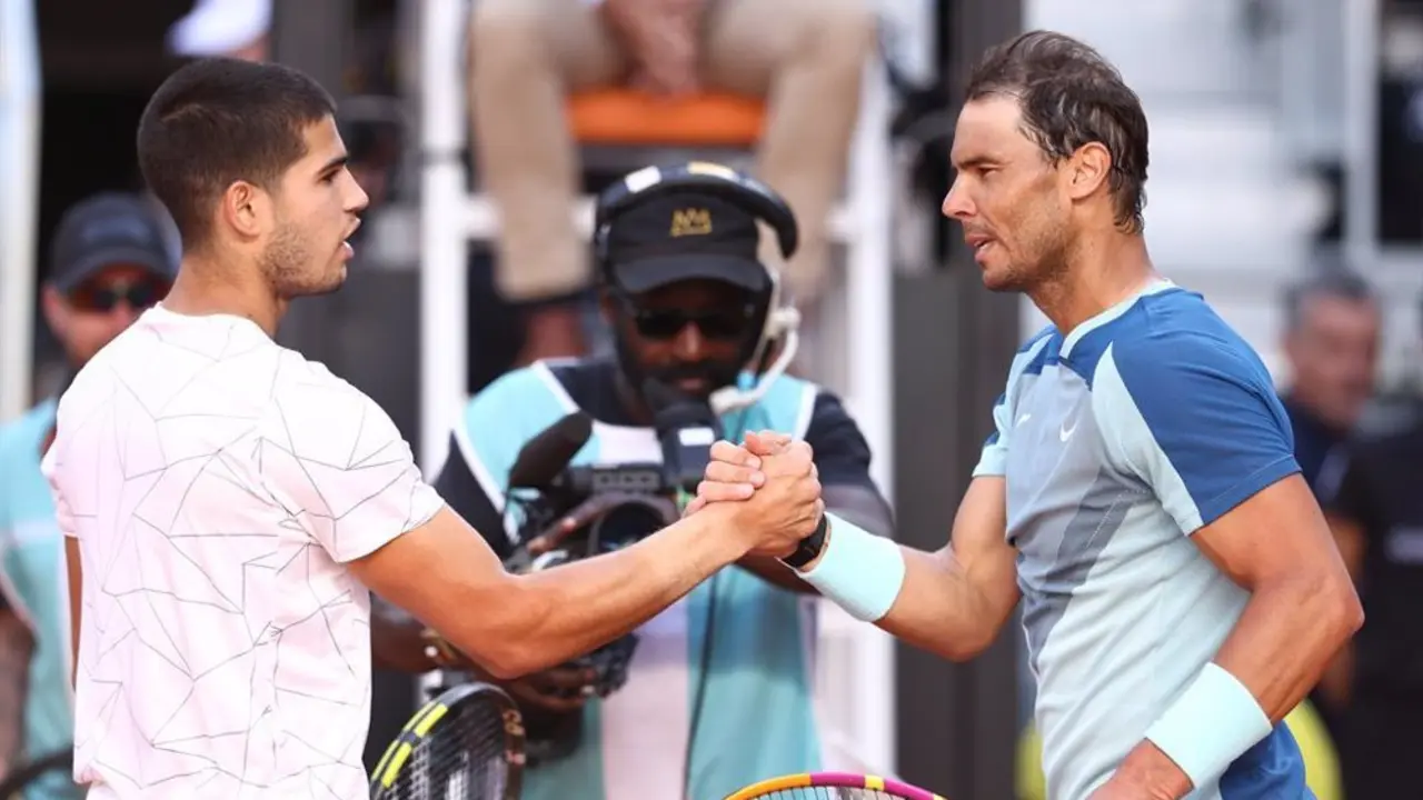 Alcaraz y Nadal d&aacute;ndose la mano en una pista de tenis