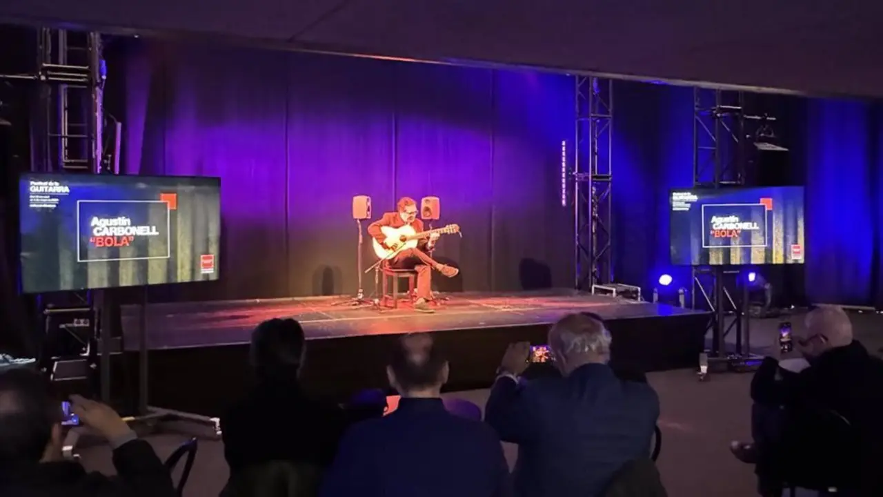 Se&ntilde;or sobre un escenario tocando la guitarra