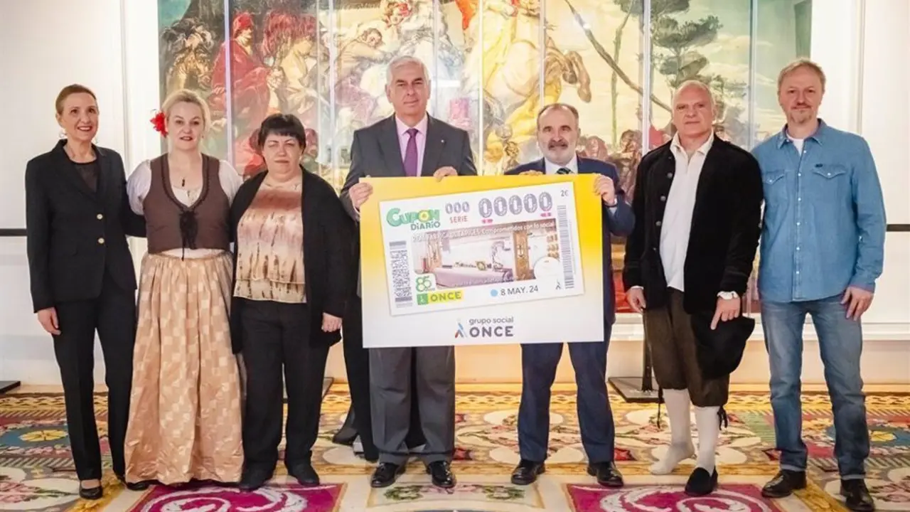 Personas sosteniendo un cup&oacute;n de la ONCE de gran tama&ntilde;o en la Real F&aacute;brica de Tapices