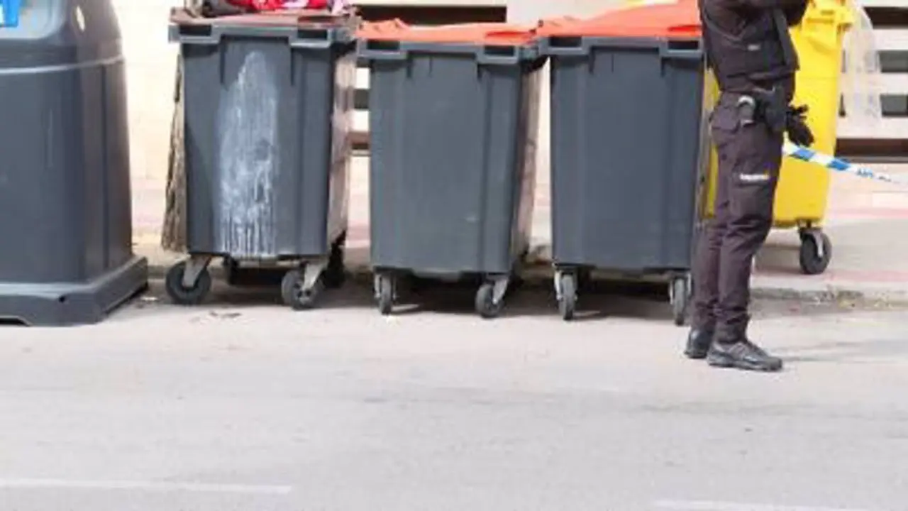 Agente de seguridad frente a contenedores de basura