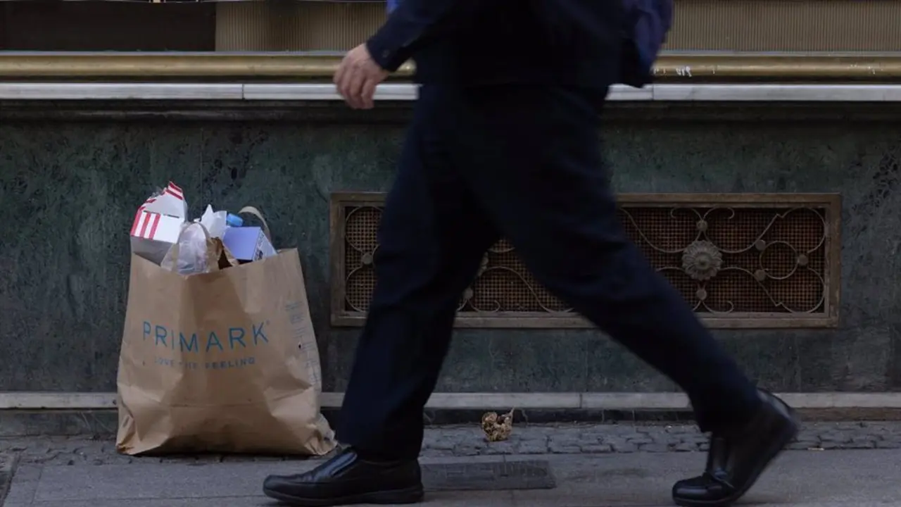 Hombre caminando por calle con bolsas 