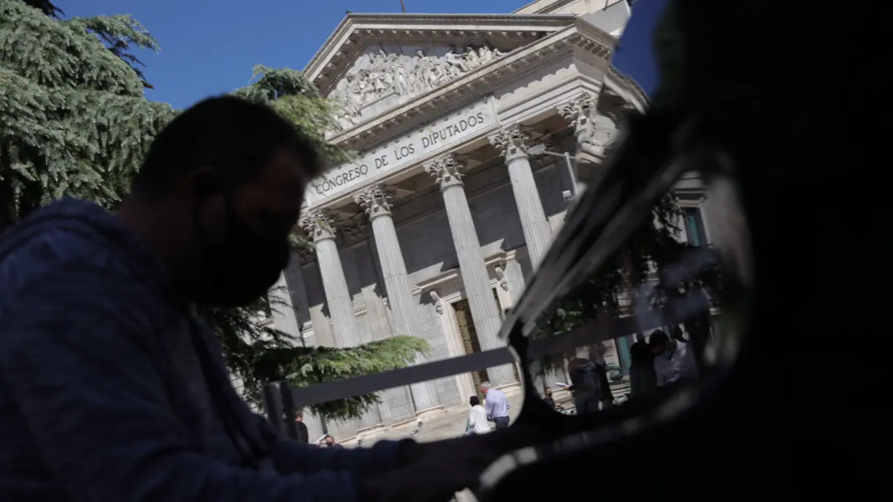 Hombre tocando el piano en plena calle con el Congreso de los Diputados de fondo