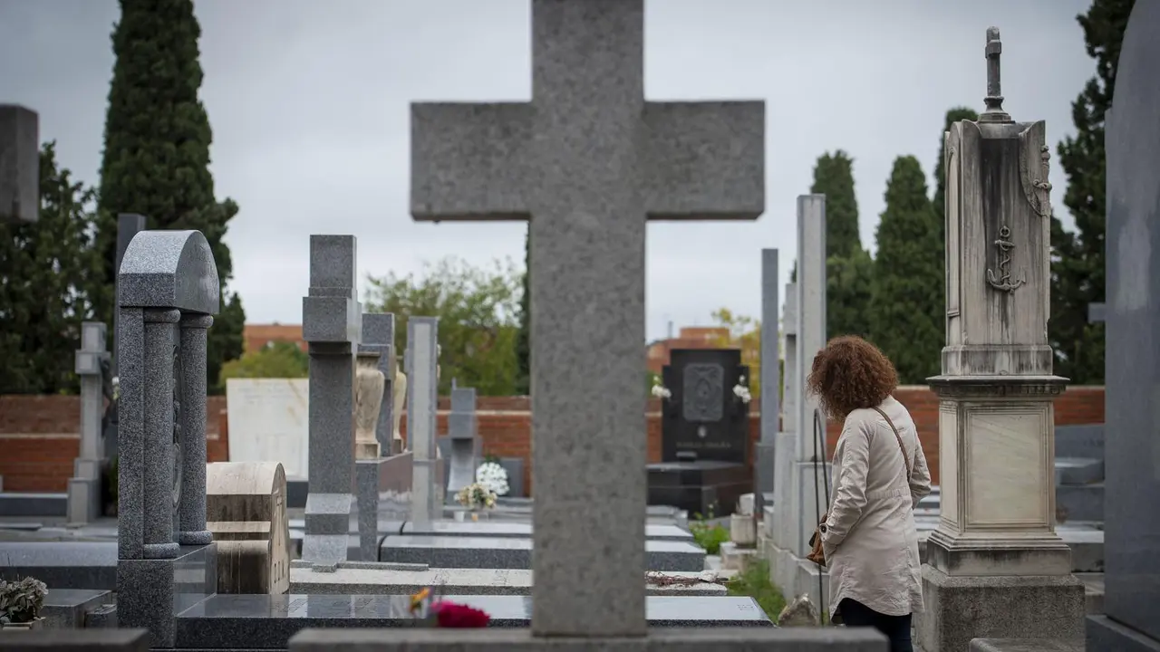 Una mujer delante de una l&aacute;pida en un cementerio.