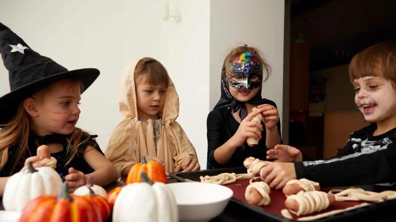 Varios ni&ntilde;os disfrazados de Halloween alrededor de una mesa con comida