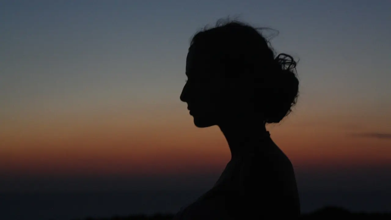 Imagen de archivo de una mujer a contraluz en un atardecer.