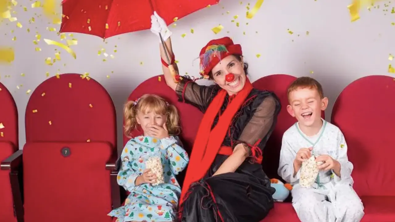 Una mujer vestida de payaso alegra junto a dos ni&ntilde;os en pijama