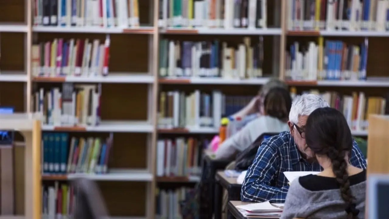 Sala de una biblioteca con dos usuarios en las mesas estudiando