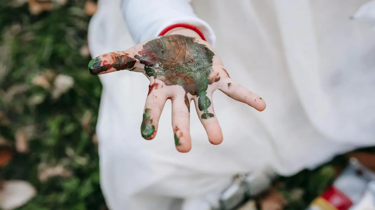 Imagen de archivo de la mano de un menor pintada de verde y marr&oacute;n.