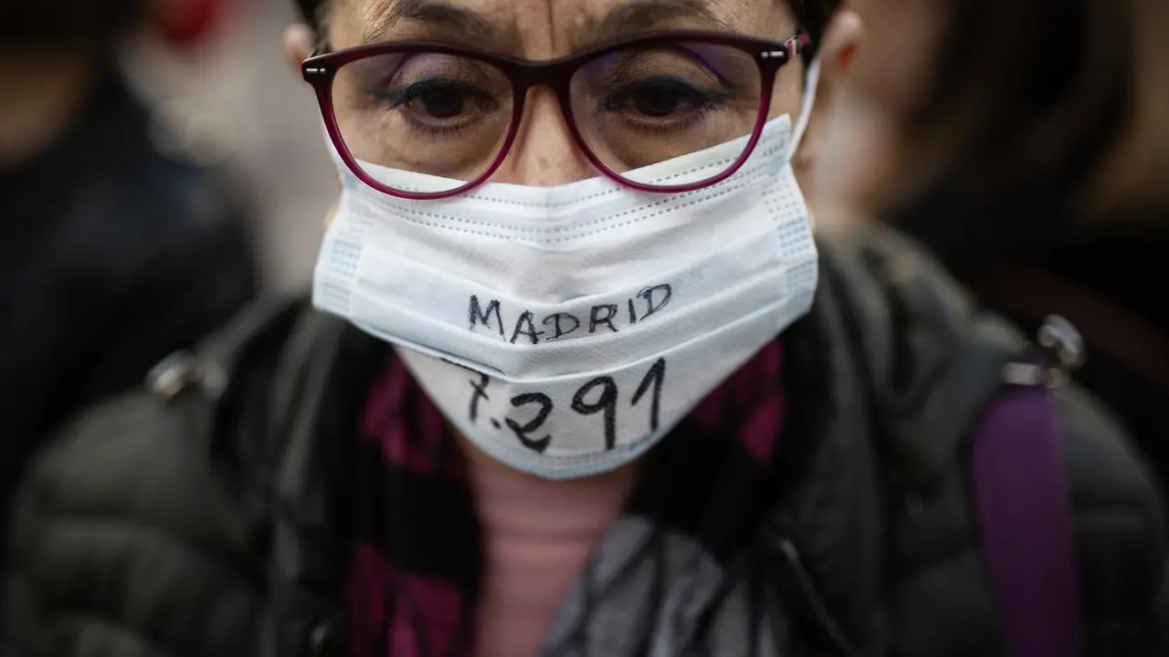 Una manifestante viste con una mascarilla con una cifra de fallecidos en la Comunidad.