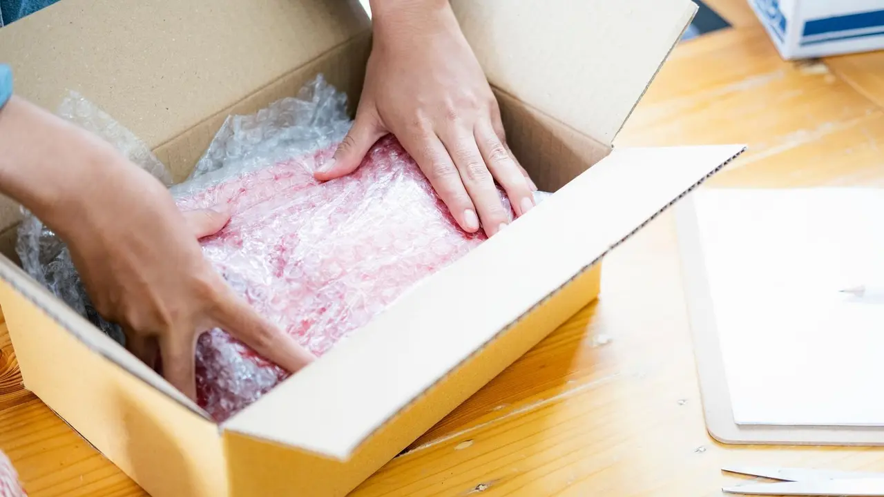 Imagen de archivo. Una persona empaquetando en una caja.