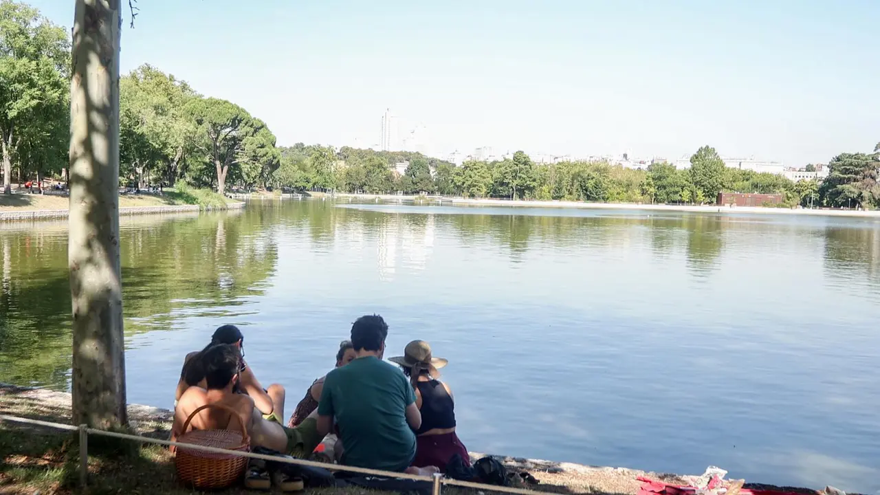 Personas sentadas en la orilla del lago de la casa de campo. Imagen de archivo.