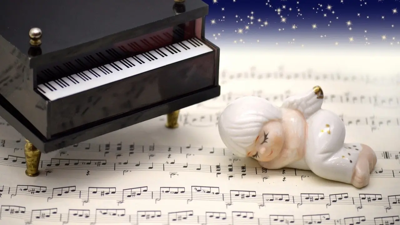 Un &aacute;ngel durmiendo sobre una partitura con un piano al lado.