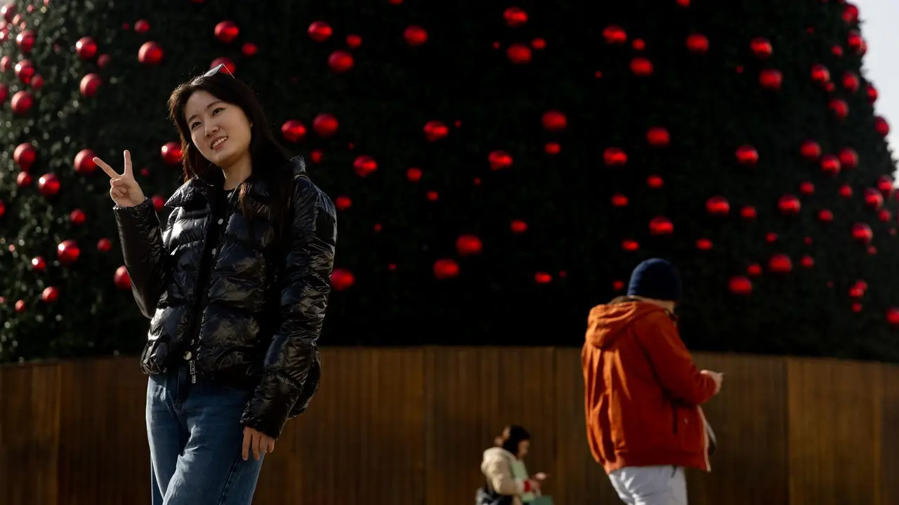 Una turista se hace una foto junto al &aacute;rbol de Navidad de la Puerta del Sol.