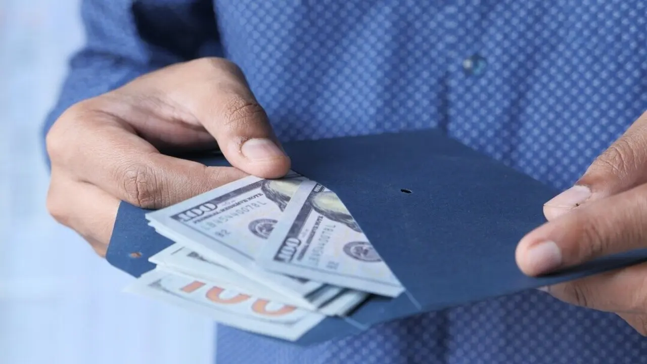 Persona poniendo dinero en efectivo en un sobre. Imagen de archivo.