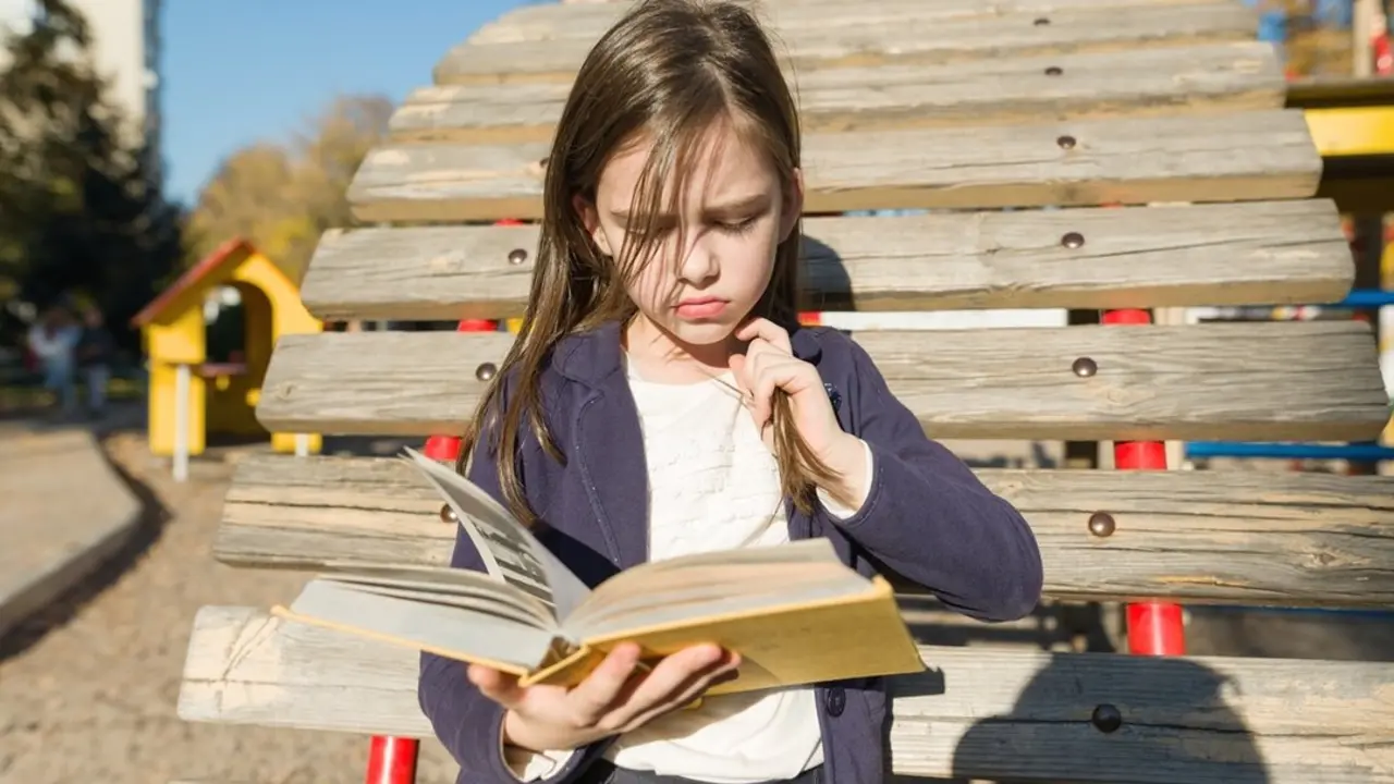 Ni&ntilde;a leyendo ofendida un libro en el parque. Imagen de archivo.