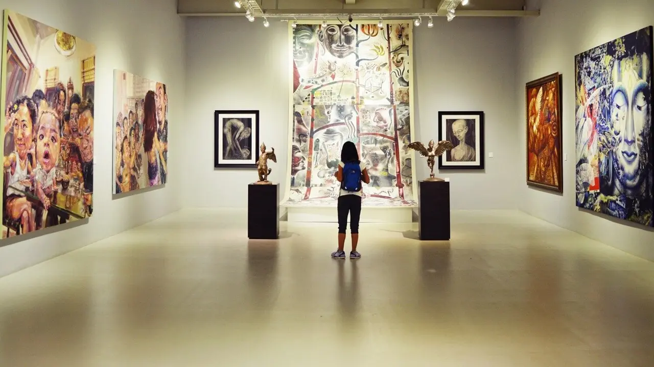 Una mujer mirando una obra de arte en un museo en imagen de archivo.