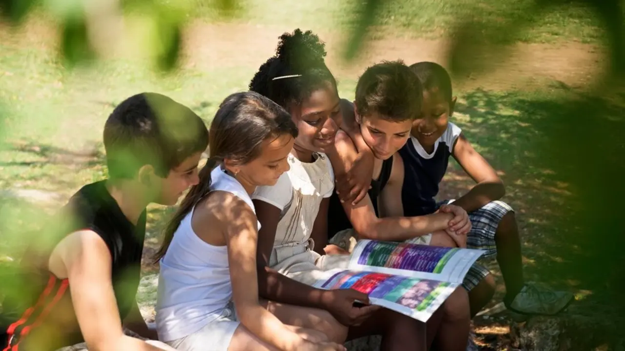 Ni&ntilde;os leyendo al aire libre. Imagen de archivo.