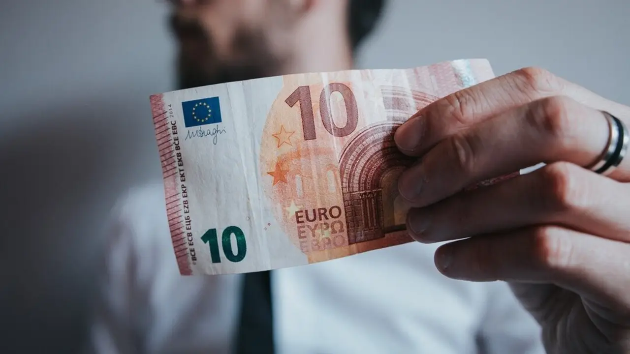 Hombre sosteniendo un billete de diez euros. Imagen de archivo.